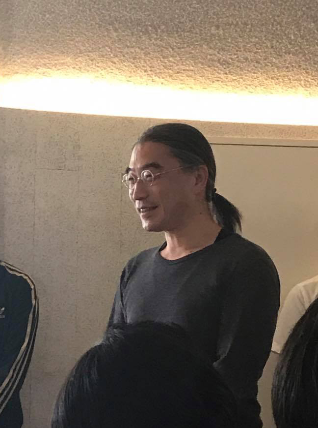 丸いメガネをかけ、髪をうしろに一つにまとめて、笑う熊澤先生